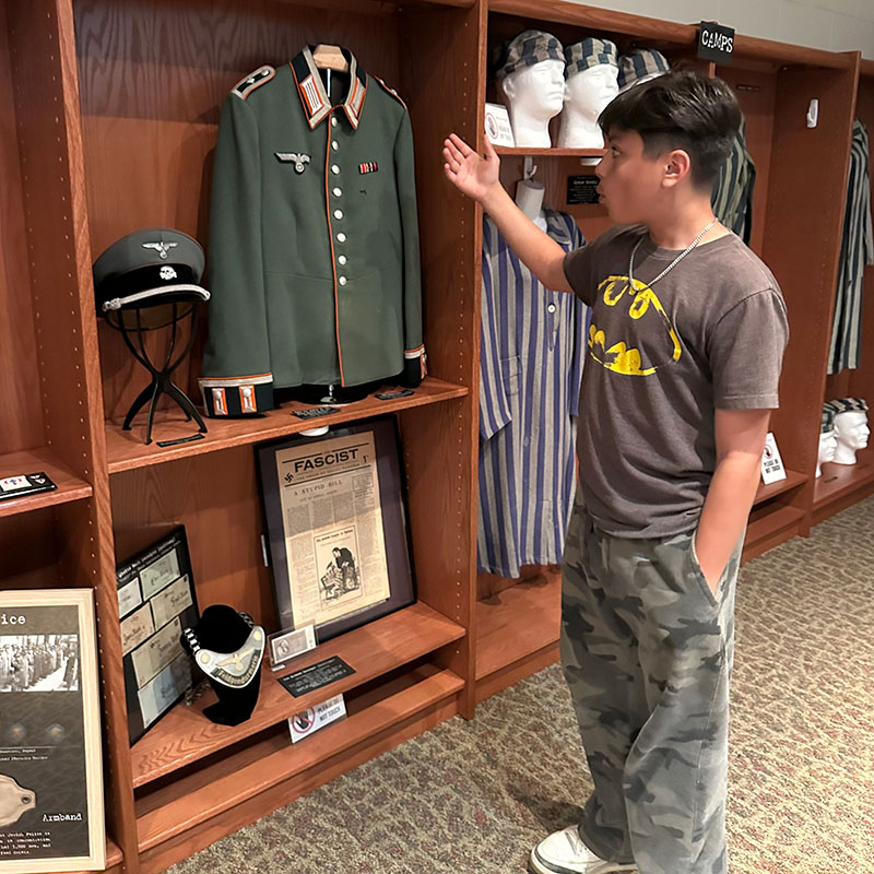 A young boy looks at a uniform at the Children's Holocaust Museum